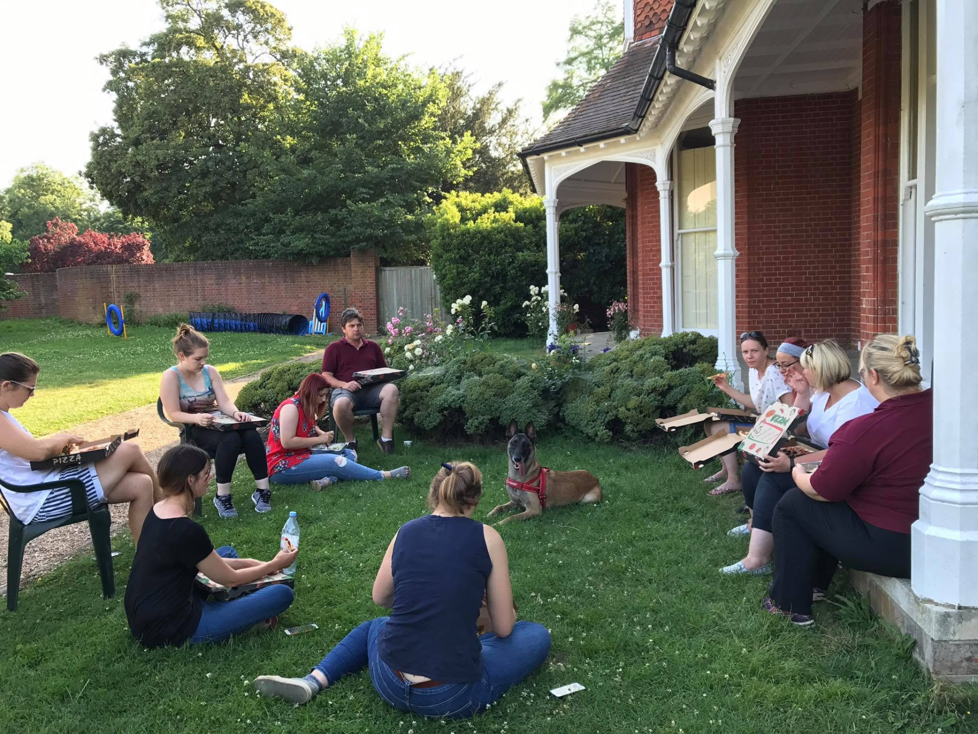 Course attendees and a Malinois taking a break in the grounds of a training venue